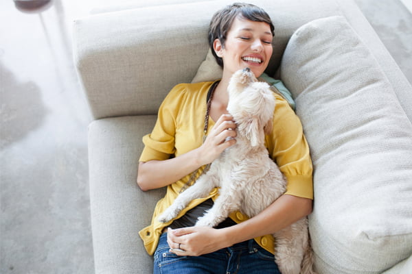 Kvinne koser med hund i sofa
